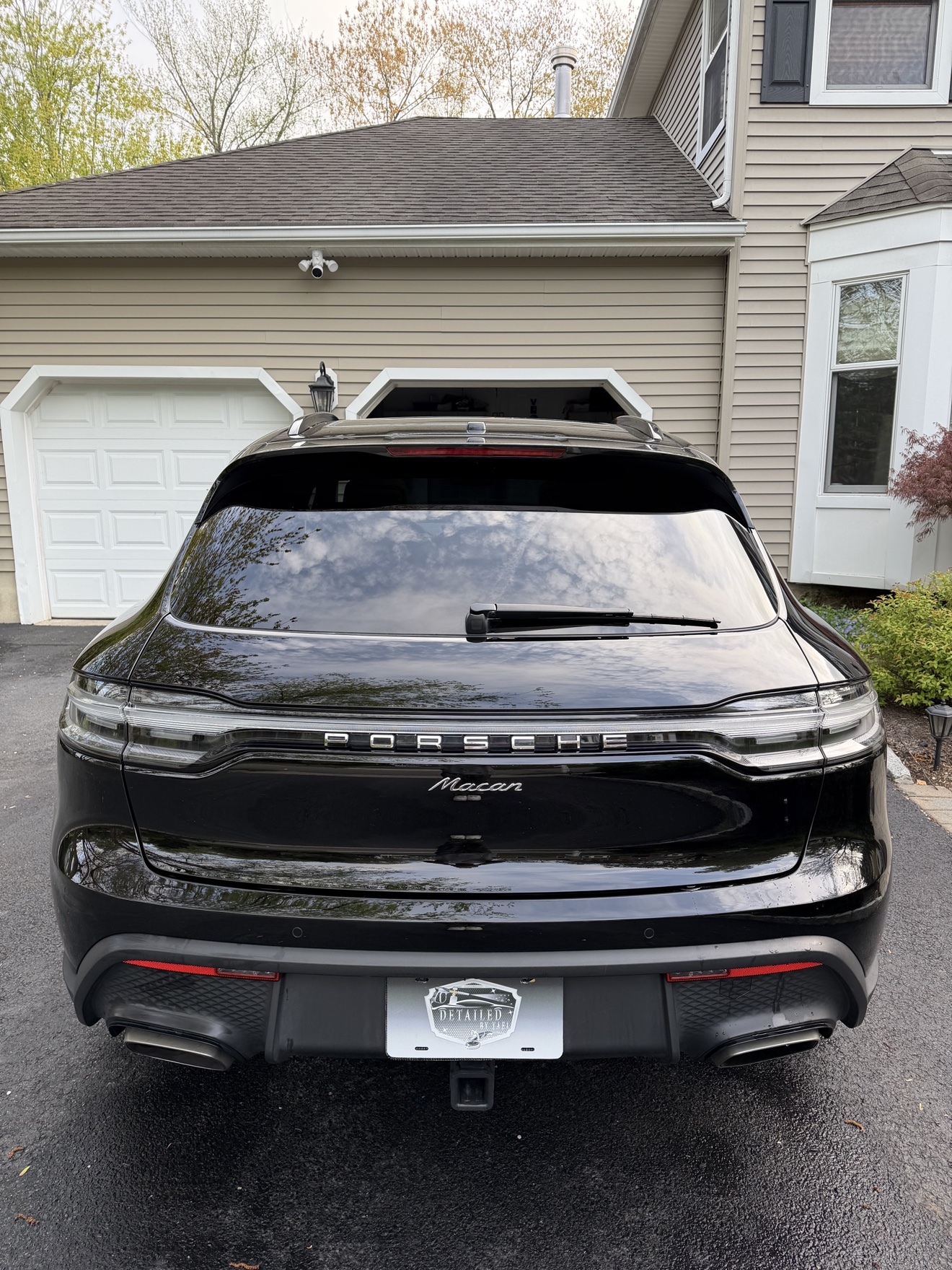Rear view of a black Porsche Macan with Detailed by Yael plate frame