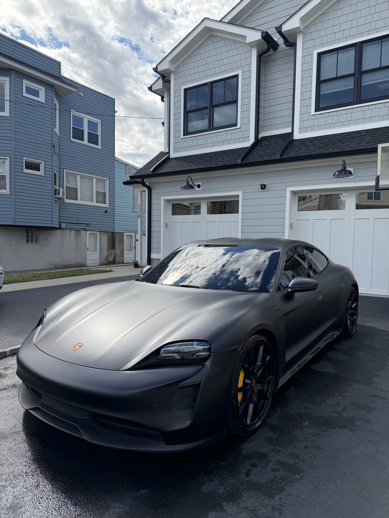 Matte black Porsche Taycan GTS front three-quarter view in a driveway