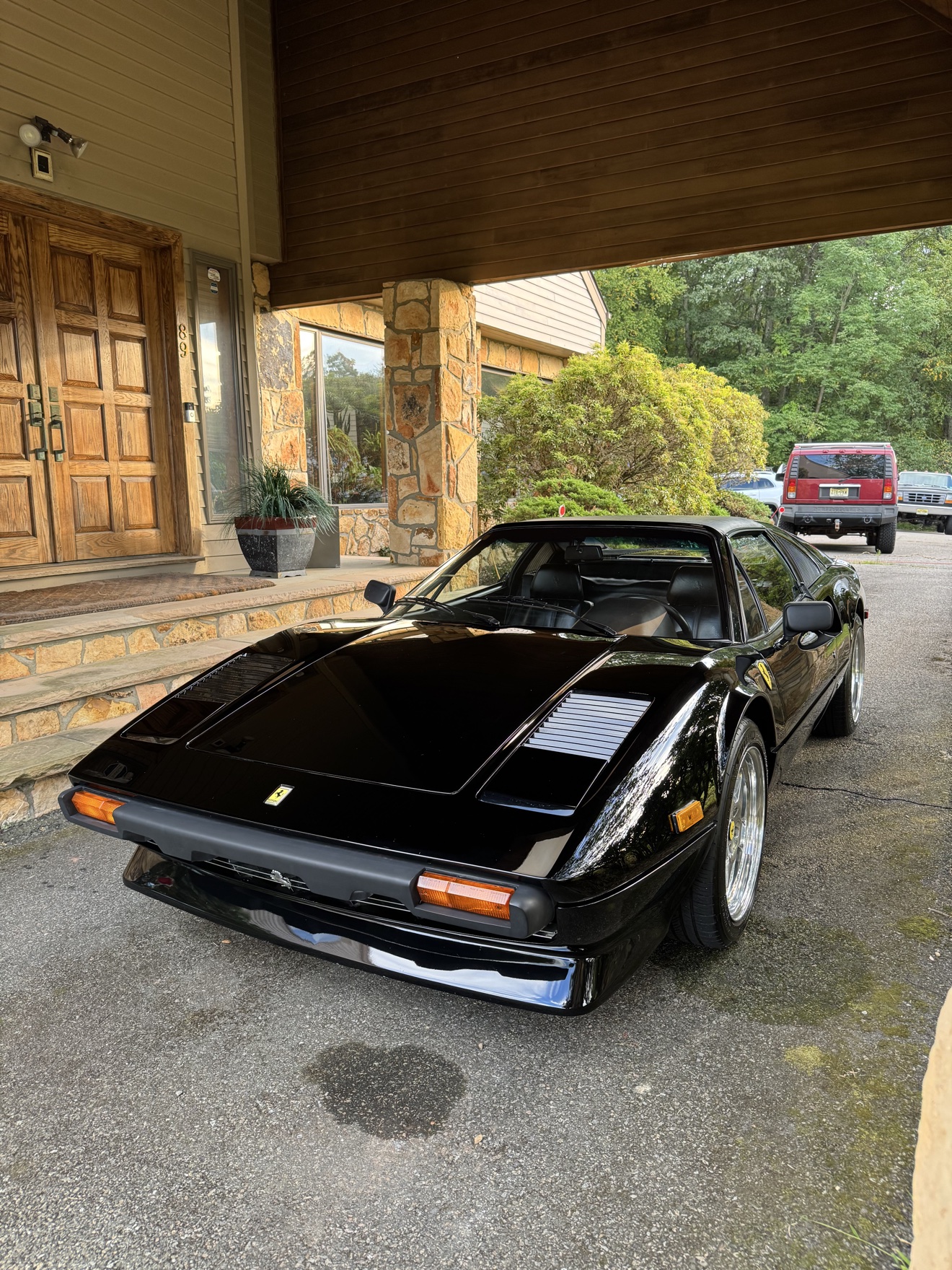 Black Ferrari 308 GTS front angle view by a house entrance
