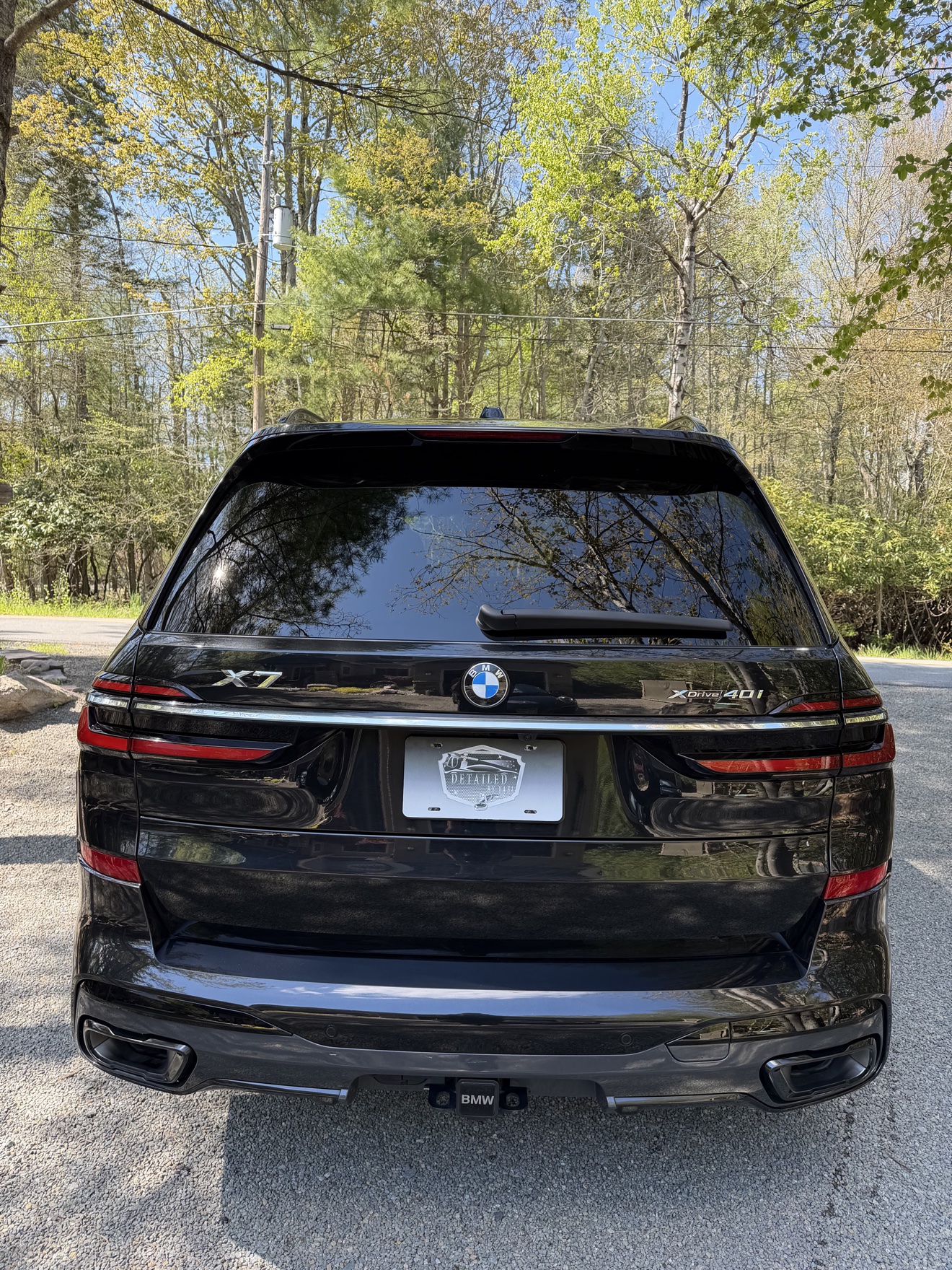 Rear view of a black BMW X7 with X7 and xDrive40i badges and Detailed by Yael plate frame