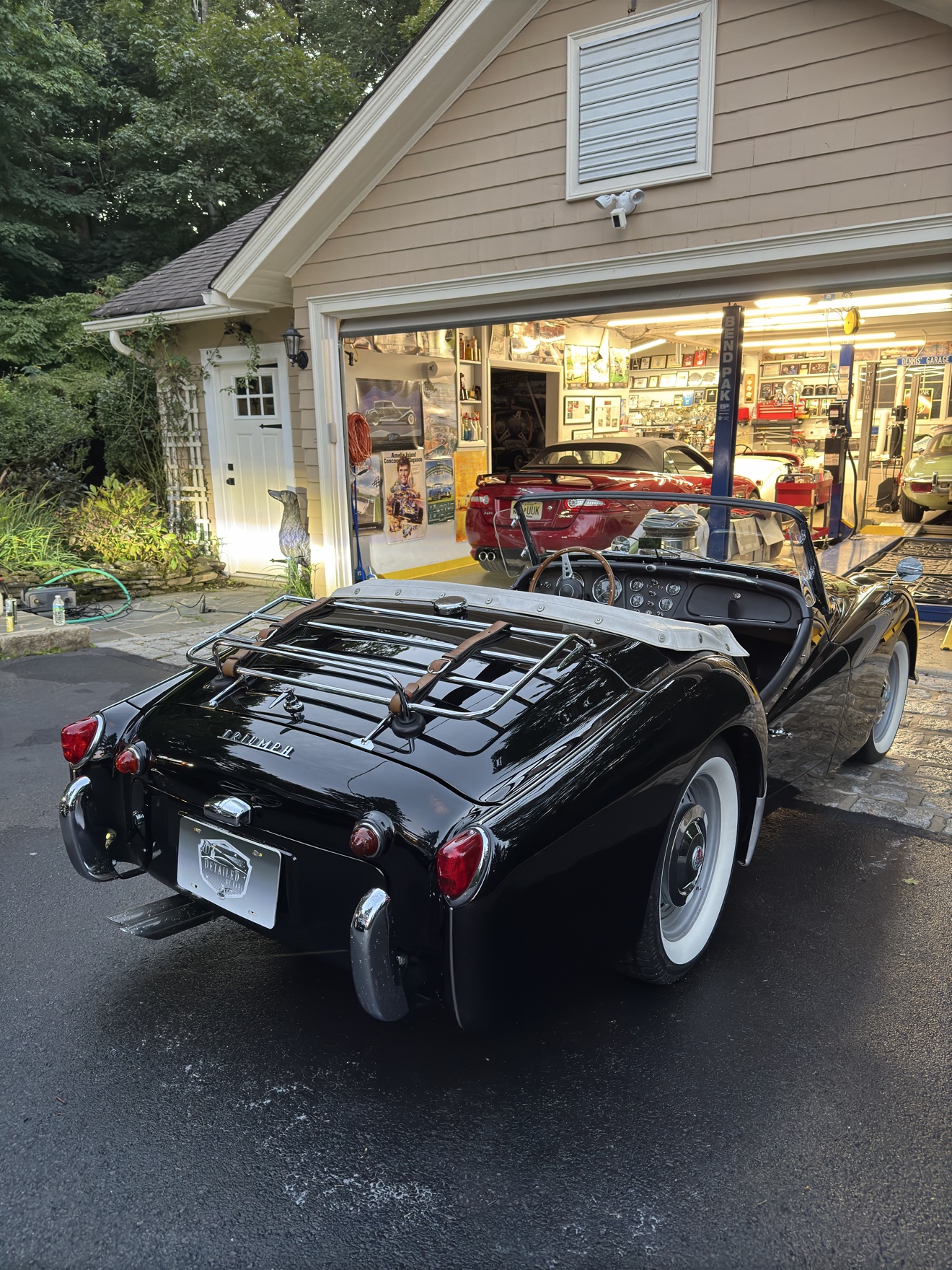 Black Triumph TR3 rear angle view by the garage after detailing