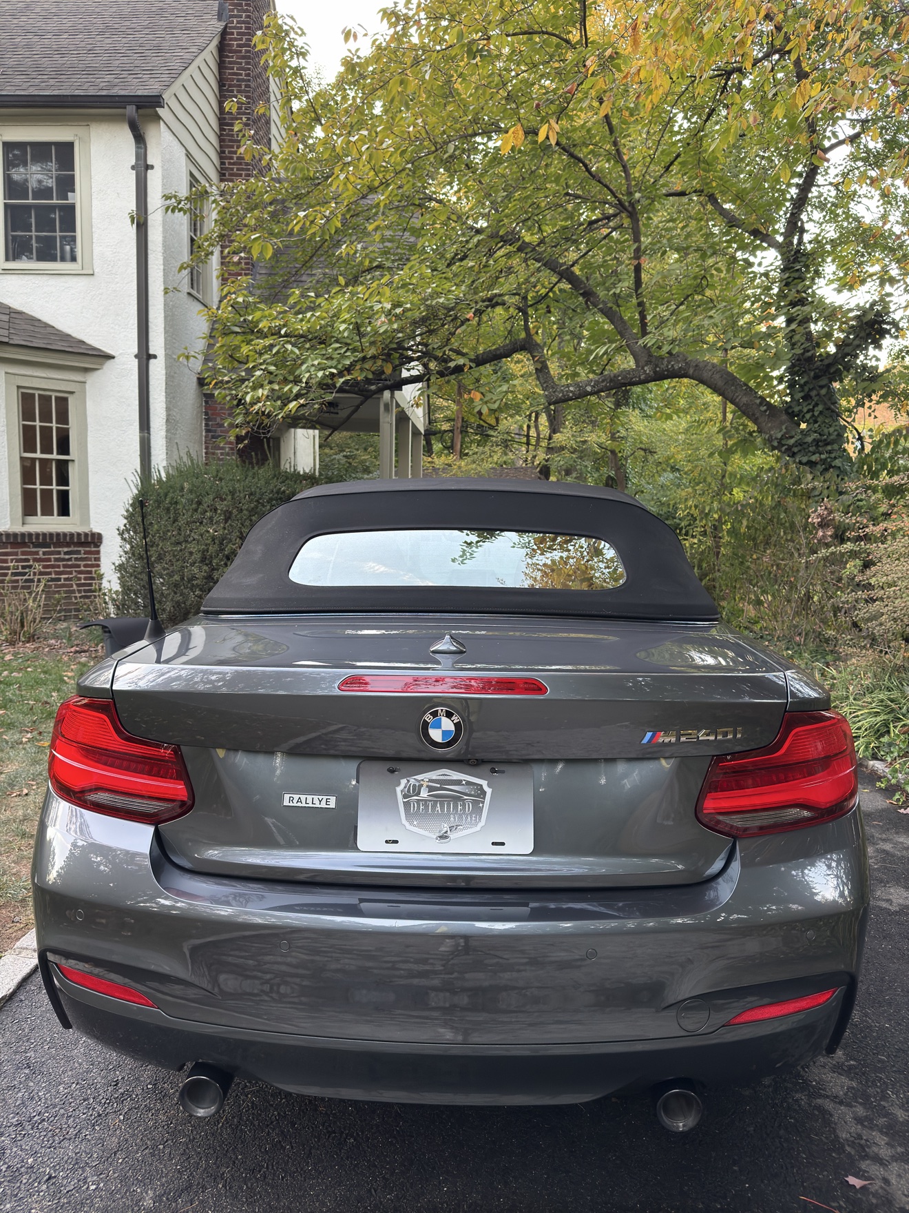 Rear view of a gray BMW M240i convertible with M240i badge and Detailed by Yael plate frame