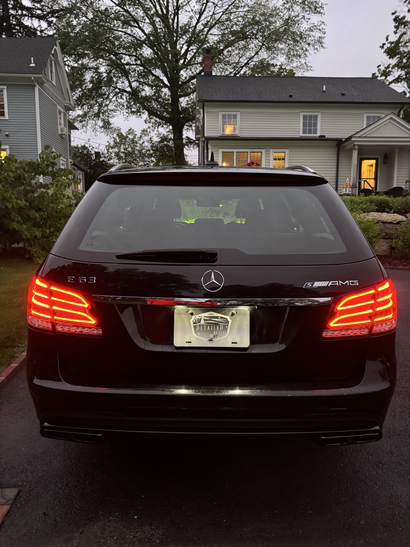 Rear view of a black Mercedes Benz E63 S AMG wagon with E 63 and AMG badges and Detailed by Yael plate frame