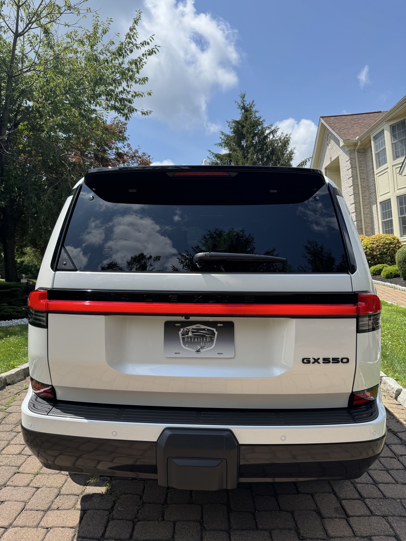 Rear view of a white Lexus GX550 with GX550 badge and Detailed by Yael plate frame