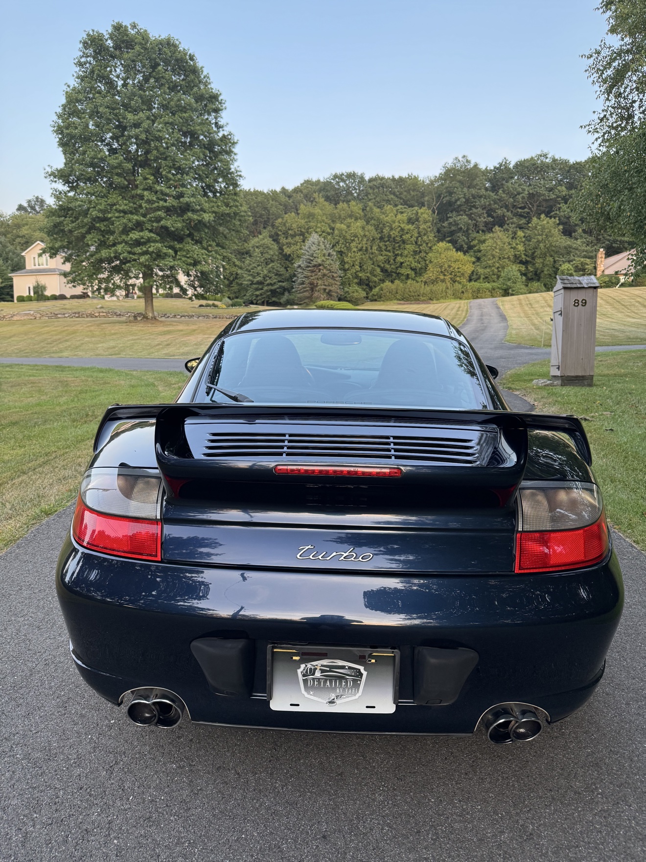 Rear view of a black Porsche 911 Turbo with turbo script and Detailed by Yael plate frame