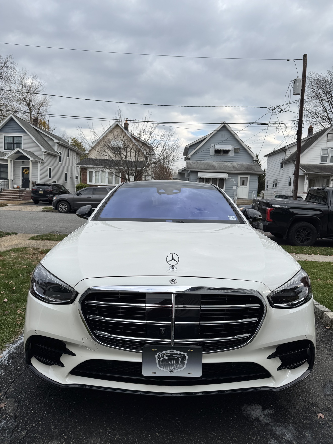 Front view of a white Mercedes-Benz S580 with Detailed by Yael plate frame
