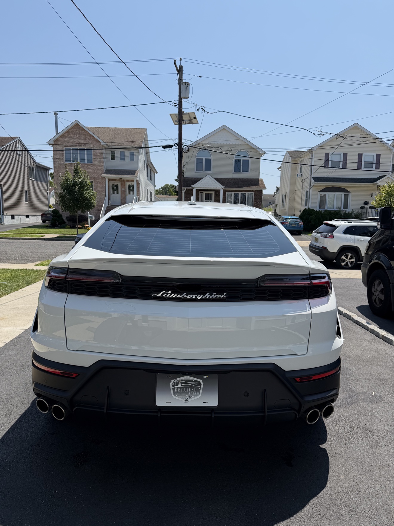 White Lamborghini Urus rear view with Detailed by Yael plate frame