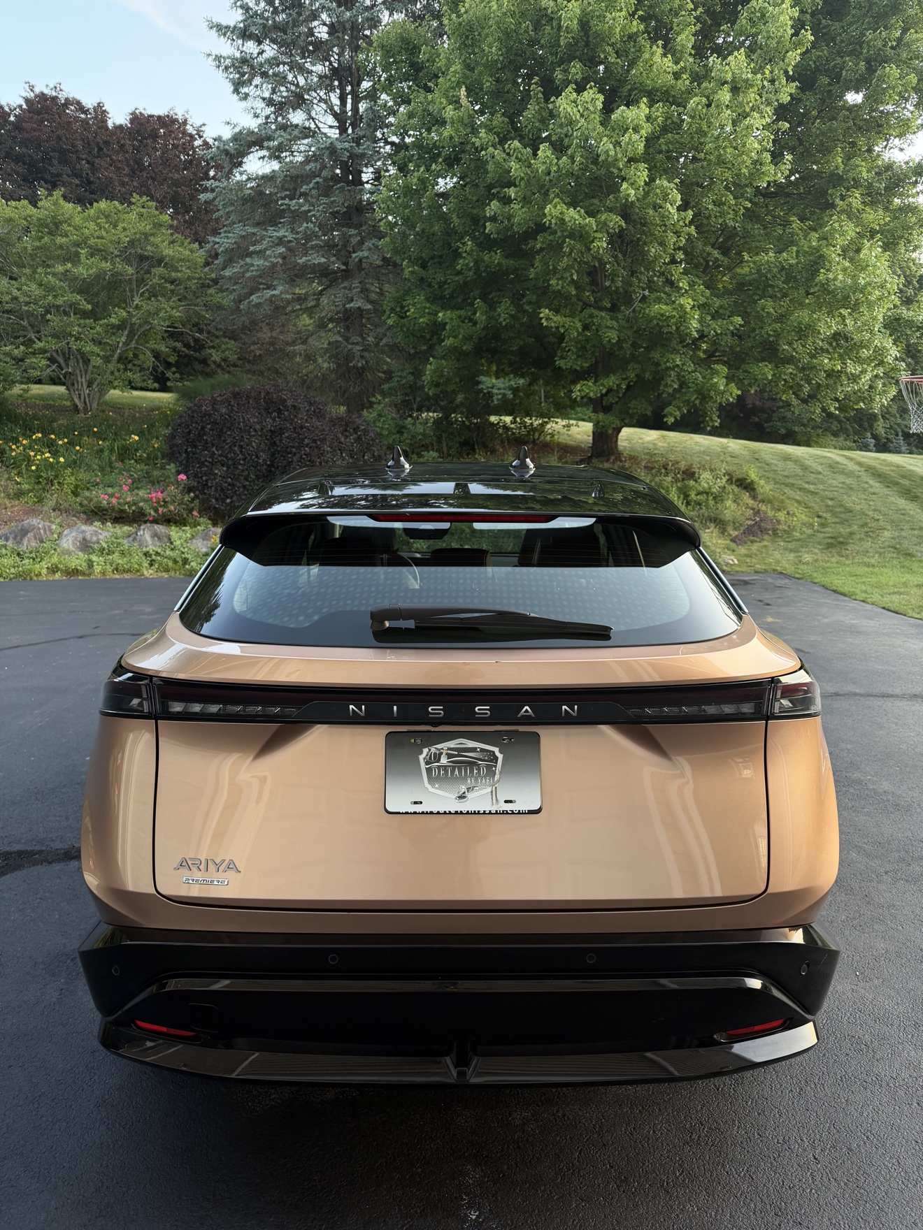 Rear view of a copper Nissan Ariya with full-width light bar and Detailed by Yael plate frame