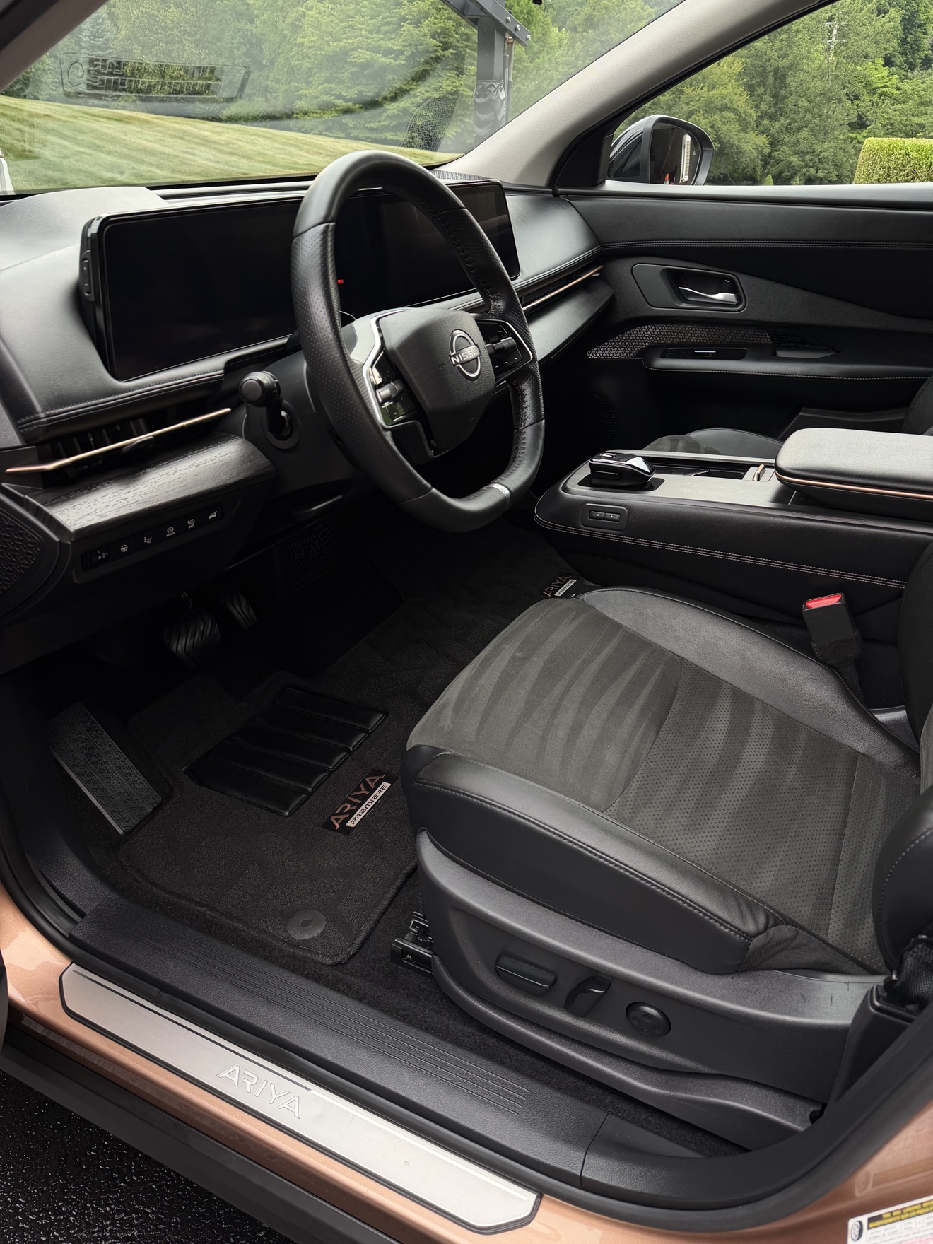Nissan Ariya driver cockpit with black interior and Ariya sill plate