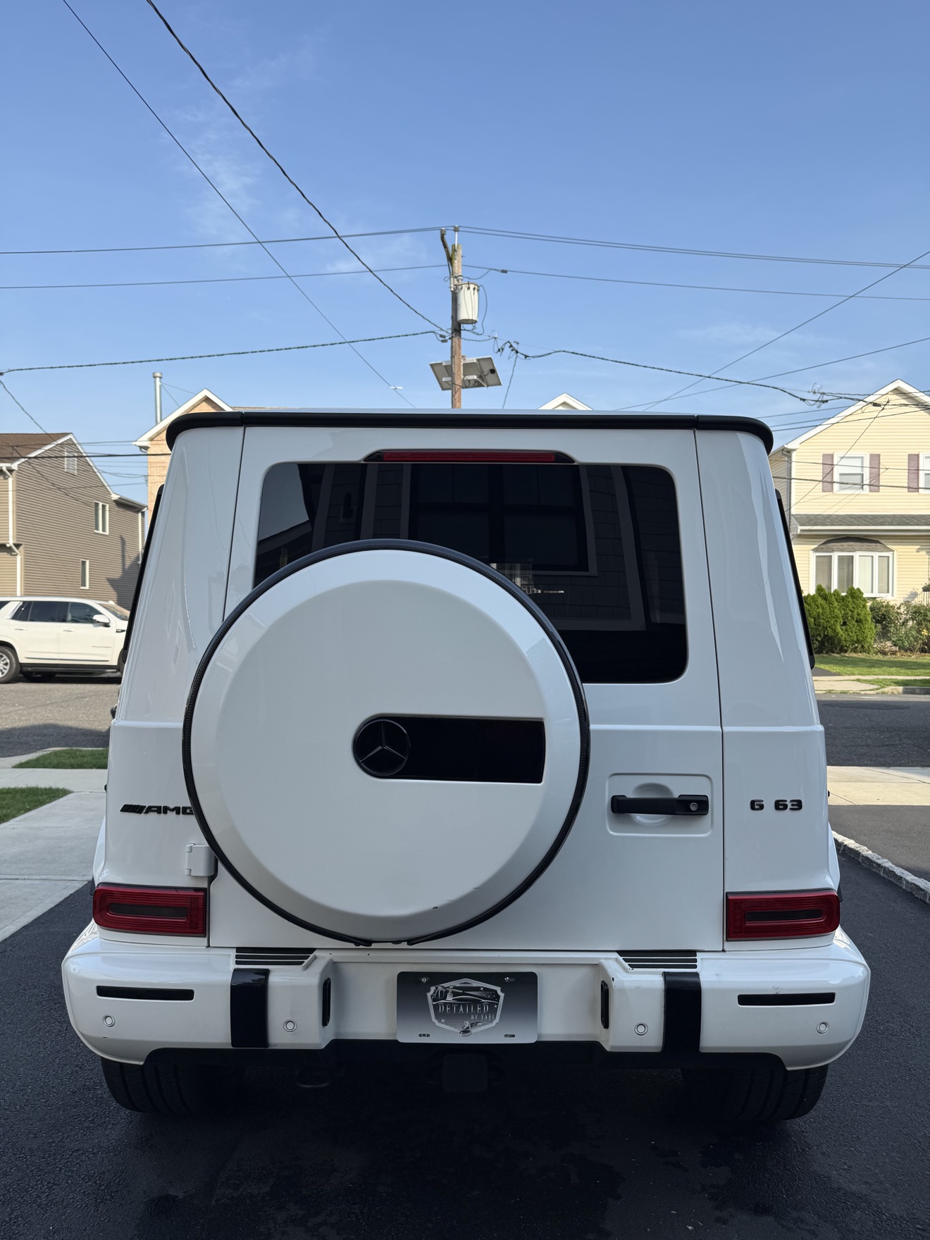 White Mercedes-AMG G 63 rear view with Detailed by Yael plate frame