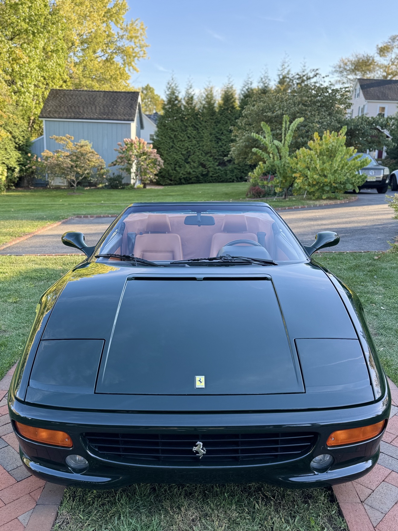 Front view of a dark green Ferrari F355 Spider with tan interior