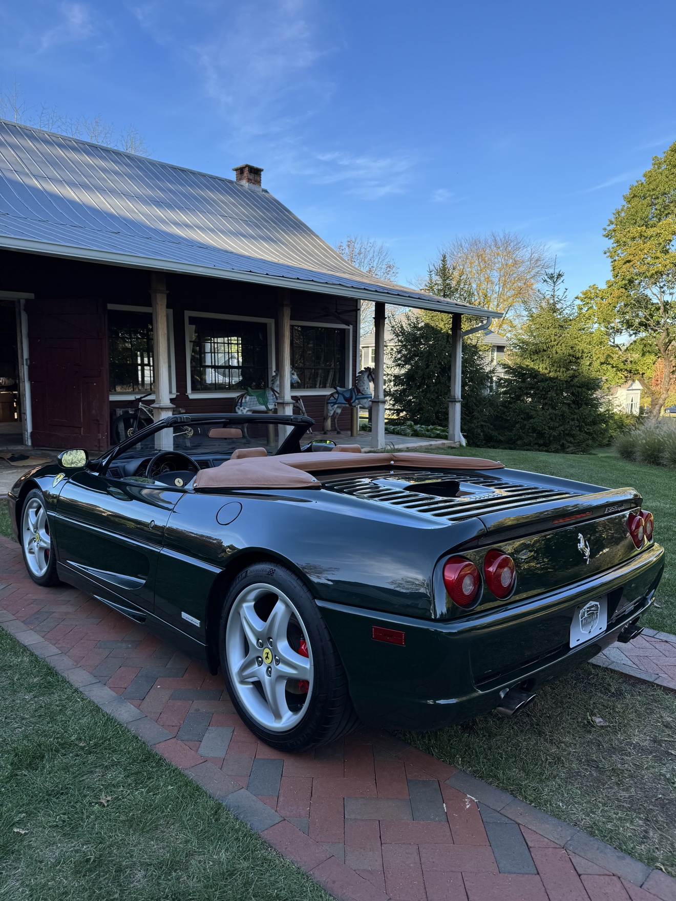 Dark green Ferrari F355 Spider rear three-quarter view with tan soft top