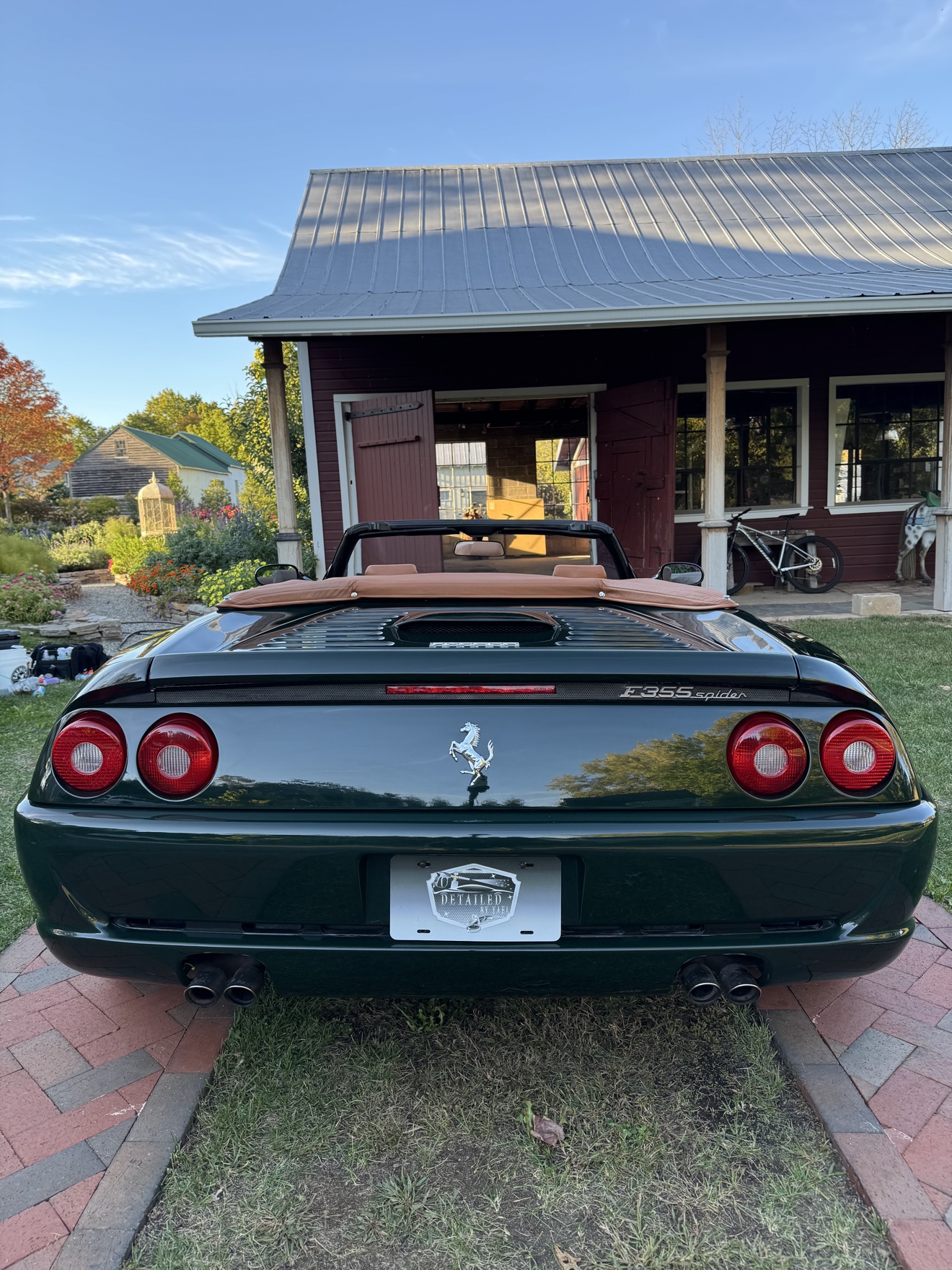 Rear view of a dark green Ferrari F355 Spider with Detailed by Yael plate frame