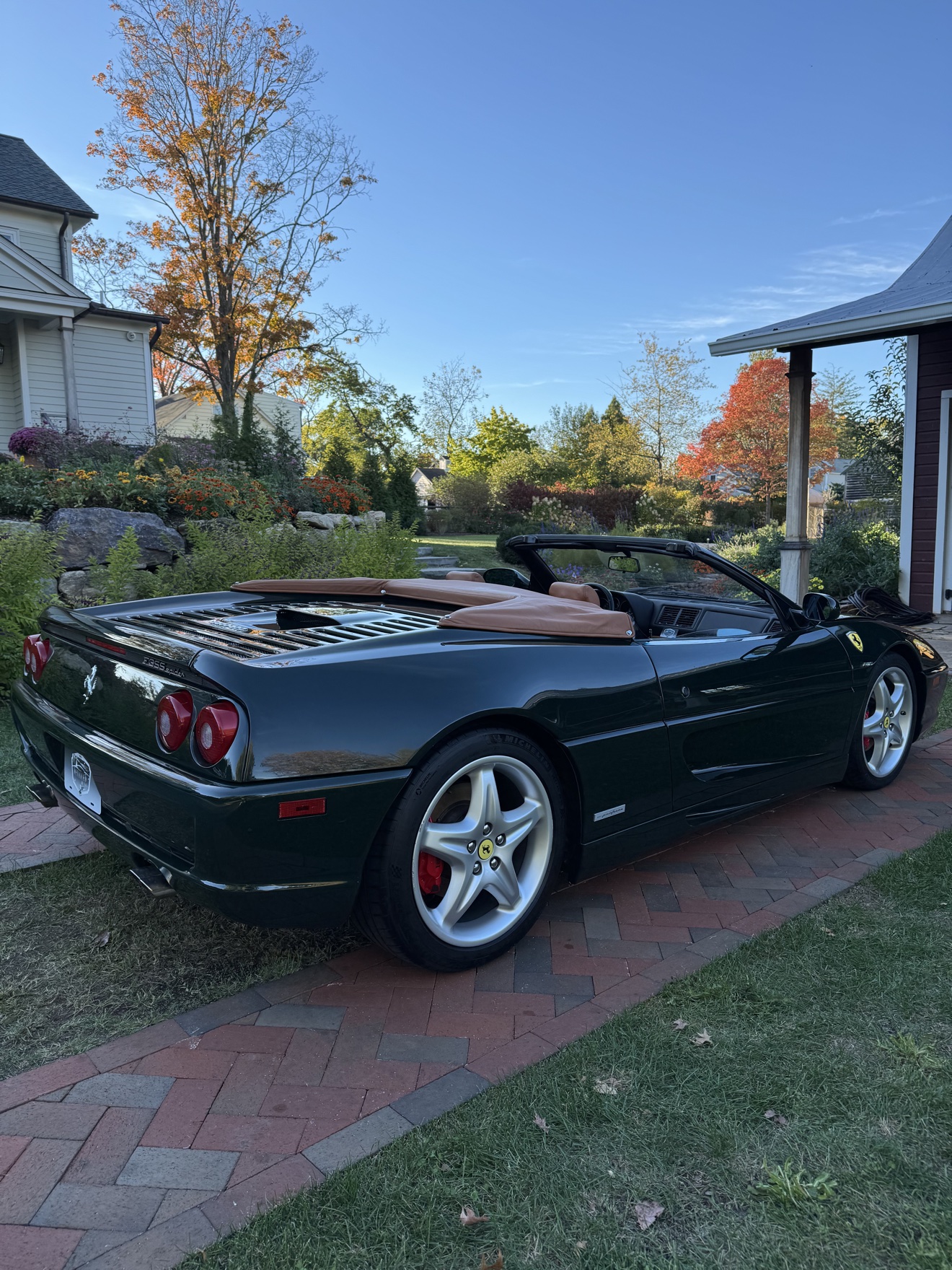 Dark green Ferrari F355 Spider rear angle view in autumn sunlight